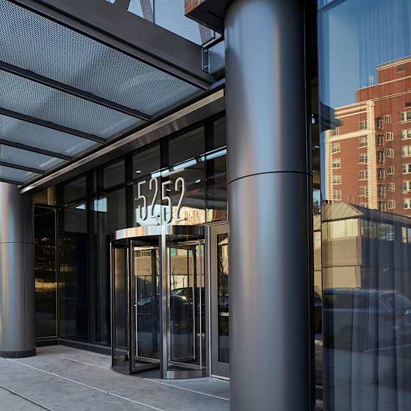 the image shows a modern building entrance with a glass door and a sign that reads