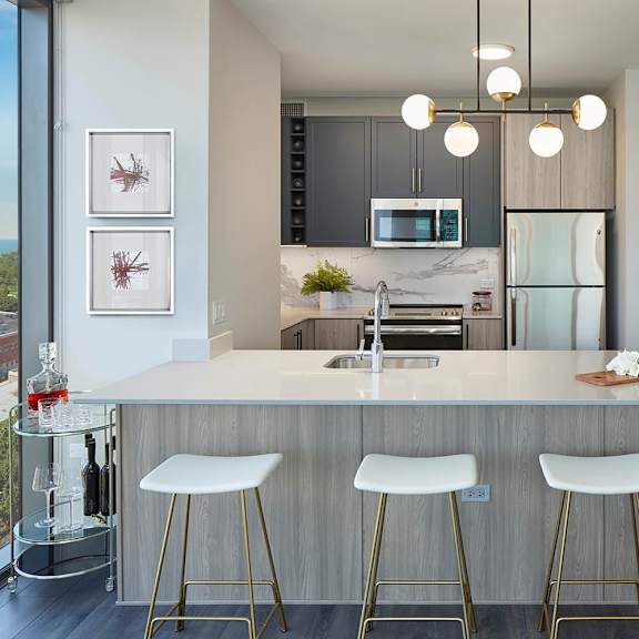 a kitchen with a bar area featuring a white counter and bar stools.
