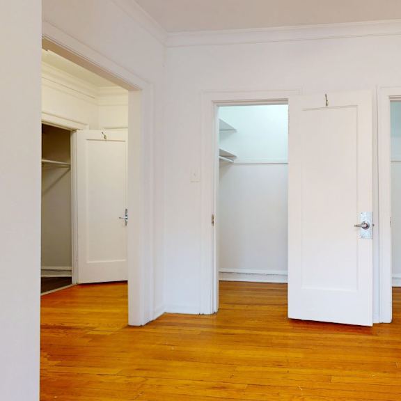 three white doors in a room with wooden floors.