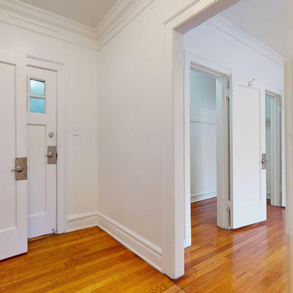 a hallway with white doors and wooden floors.