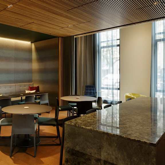 a modern dining area with a marble counter and black chairs.