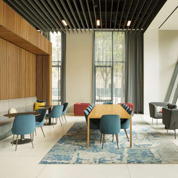 a room with a long table and chairs with a blue rug in front of it.