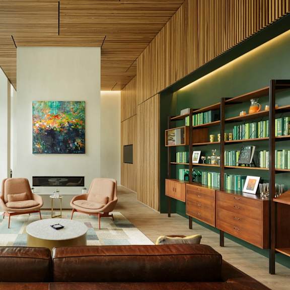 a living room with a brown leather couch and a painting on the wall.