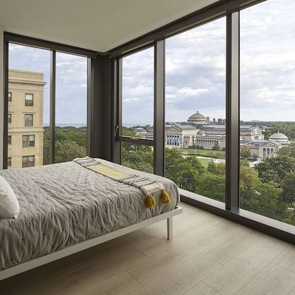 a bedroom with a large bed and a view of a cityscape through the windows.