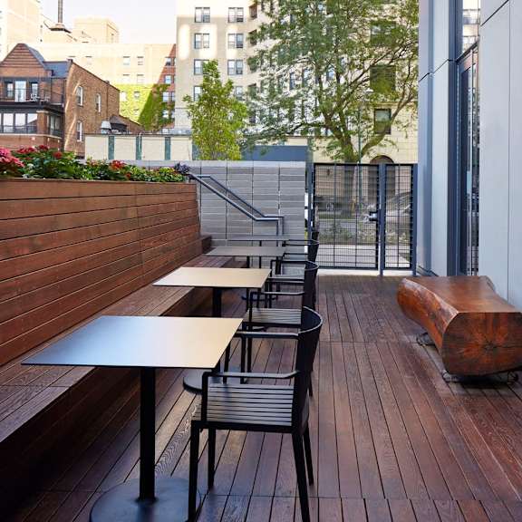a wooden deck with a bench and chairs.