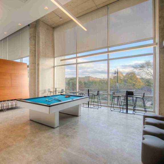 a billiard table is in the middle of a room with a wooden wall and a glass wall.