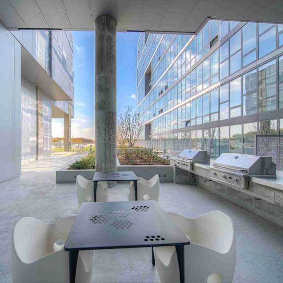 a modern outdoor seating area with a table and chairs in front of a glass building.