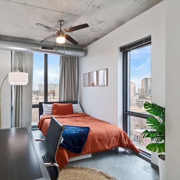 a bedroom with a bed, a lamp, and a ceiling fan.