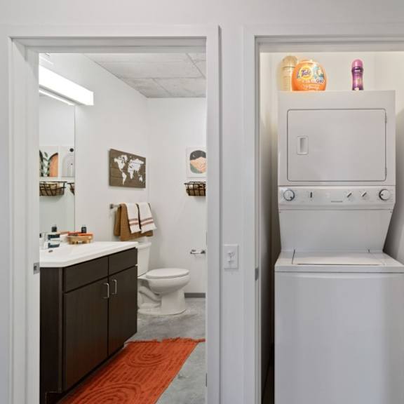 a white refrigerator is in a narrow hallway between two doors.