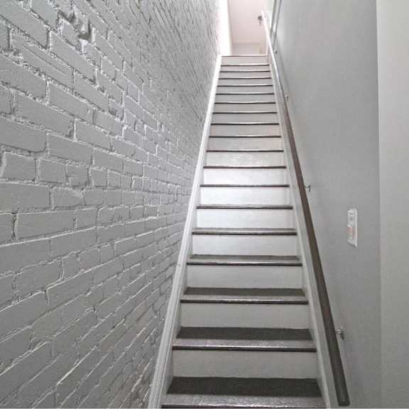 a staircase with a brick wall on the left side.