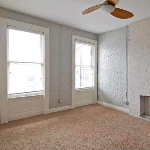 a room with a white brick wall and a ceiling fan.
