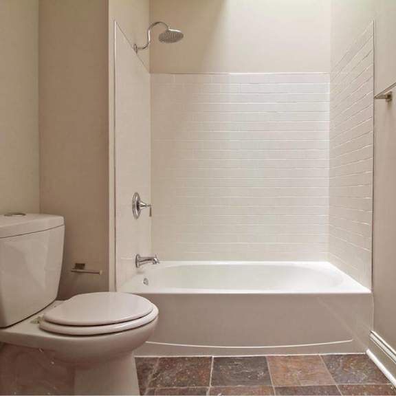 a white toilet sits next to a white bathtub in a bathroom.