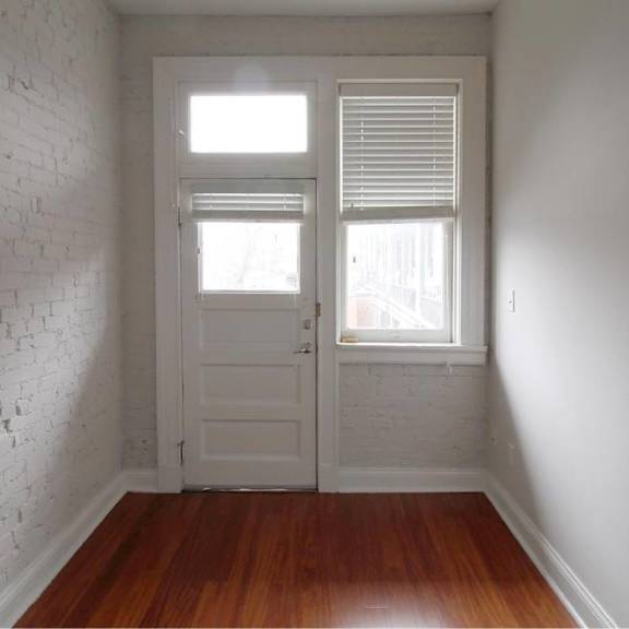 a white door with a window above it in a room with wooden floors.