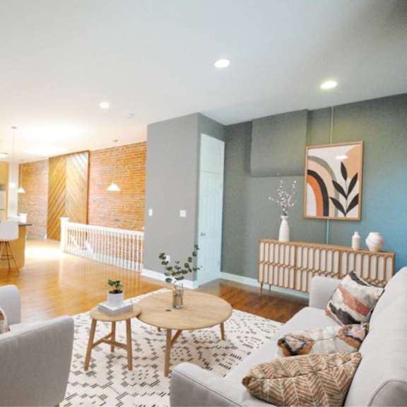 a living room with a grey couch, a wooden coffee table, and a kitchen area in the background.