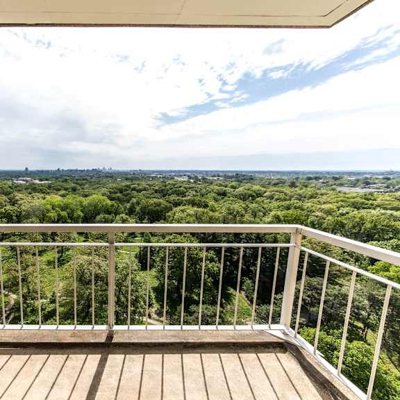 a balcony with a view of a green landscape.
