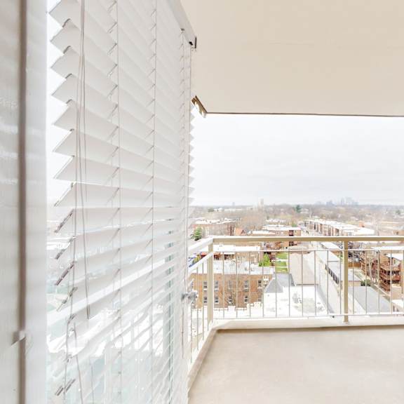 a view from a window with blinds overlooking a cityscape.