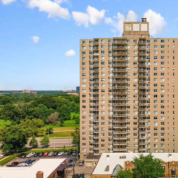 a tall building with a lot of windows is in the middle of a grassy area.