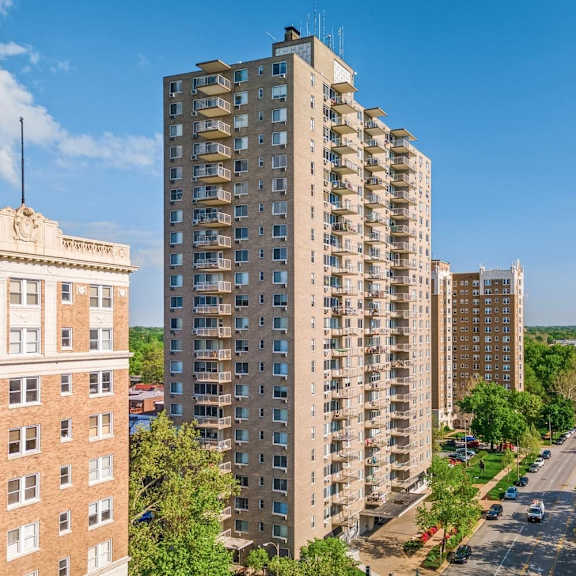 a tall apartment building stands in the middle of a street with cars parked on the side.