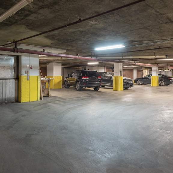a parking garage with cars parked and yellow poles.