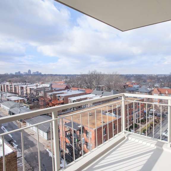 a balcony overlooks a cityscape with buildings and cars.