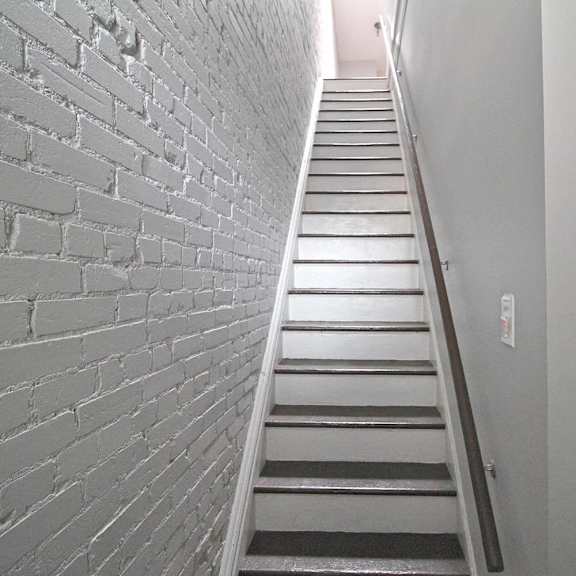 a staircase with a white brick wall on the left side.