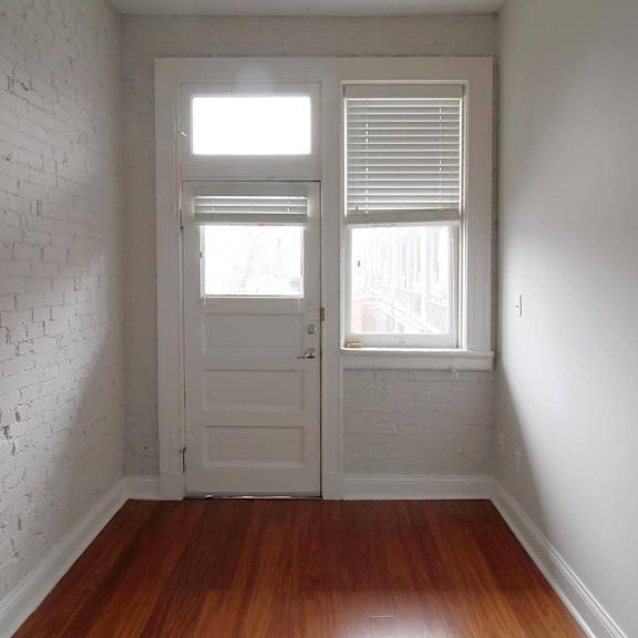 a white door with a window above it in a room with wooden floors.