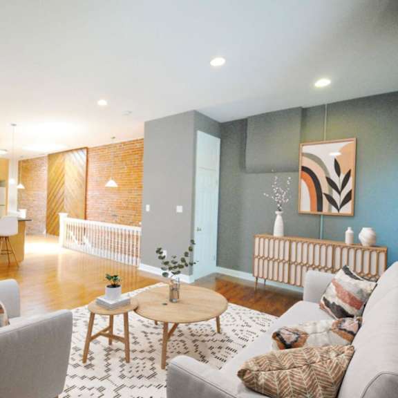 a modern living room with a grey sofa, a wooden coffee table, and a kitchen area in the background.