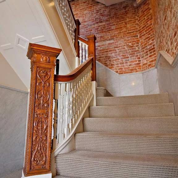 a staircase with a wooden handrail and a brick wall in the background.