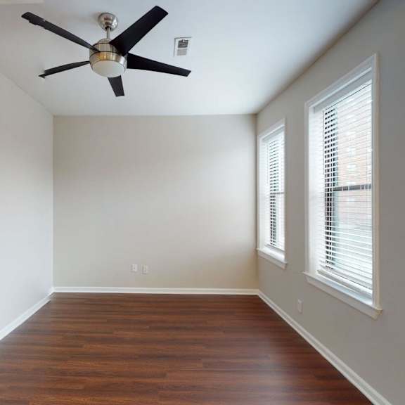 a room with a ceiling fan and wooden floors.