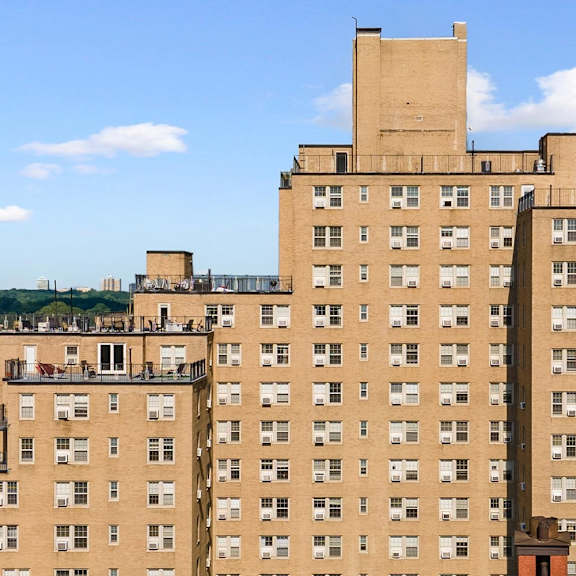a large tan building with a parking lot in front of it.