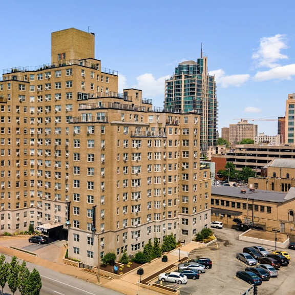a large tan building with a green roof sits in the middle of a parking lot.