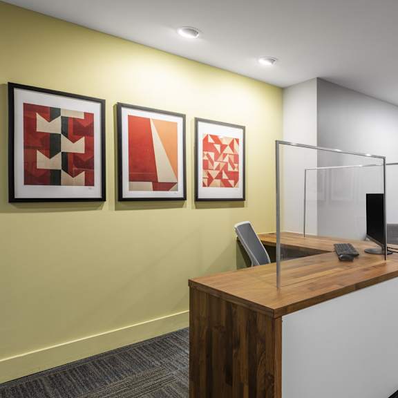 a reception area with a wooden desk and three framed artworks on the wall.