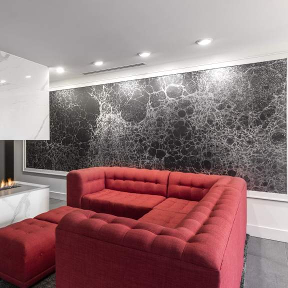a red couch sits in front of a marble fireplace.