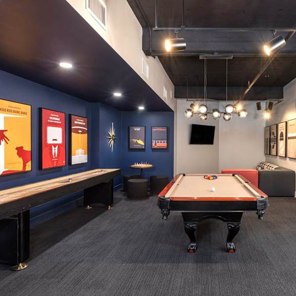 a pool table is in the middle of a room with a blue wall and a tv.