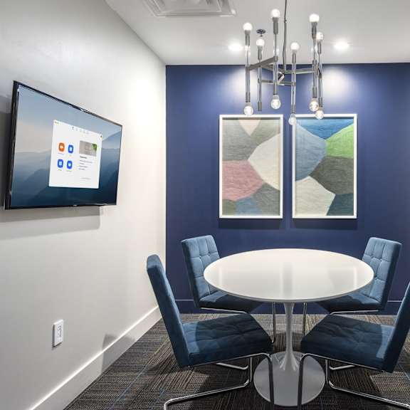 a conference room with a table, chairs, and a screen on the wall.