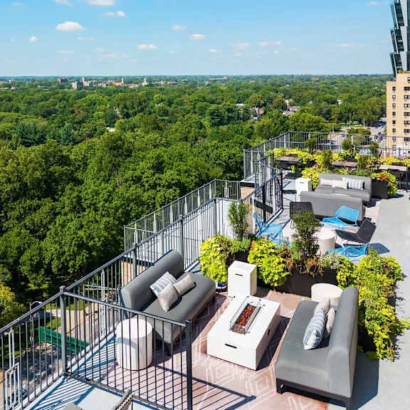 a balcony with a table and chairs overlooks a lush green forest.