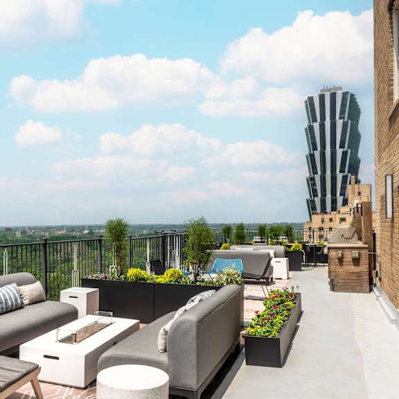 a rooftop patio with a black railing and furniture.