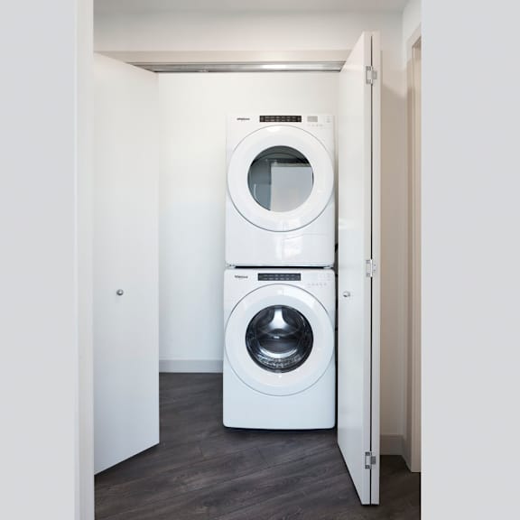 a white washing machine is in a small white room.