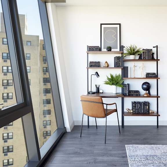 a room with a desk, chair, and shelves with various items.