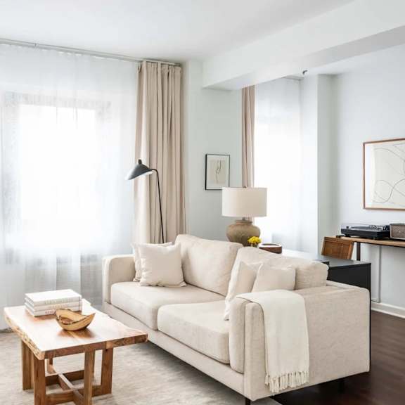 a living room with a white couch, a wooden coffee table, and a chair.