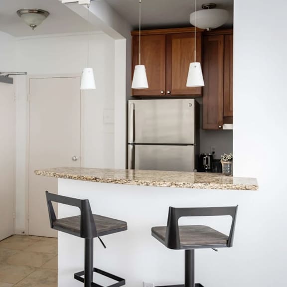 a kitchen with a refrigerator, bar stool and a framed picture on the wall.