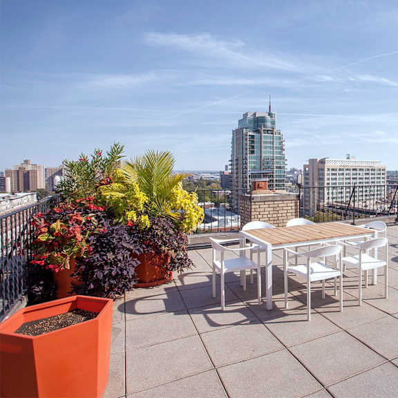 a rooftop patio with a table and chairs overlooking a city skyline.