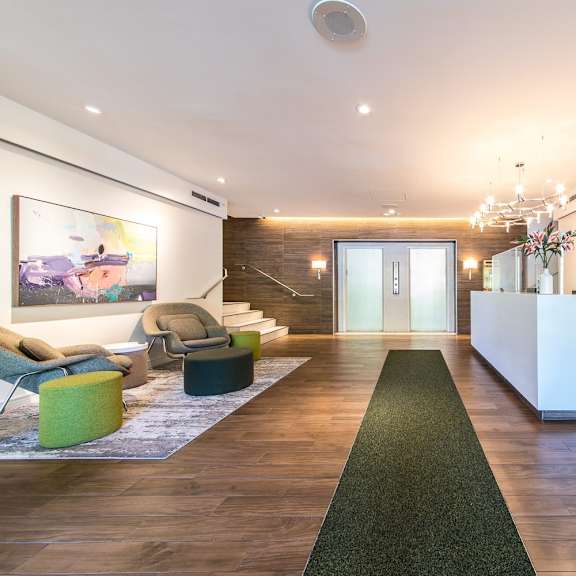 a reception area with a white reception desk and a green carpet.