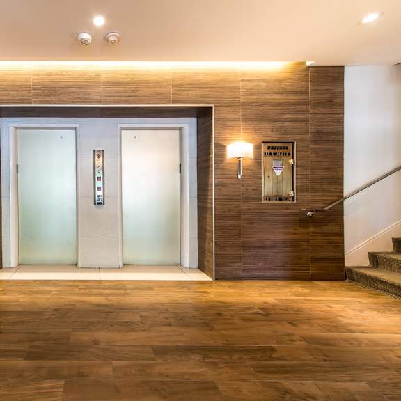 a pair of glass doors are flanked by two wall-mounted lights in a modern hallway.