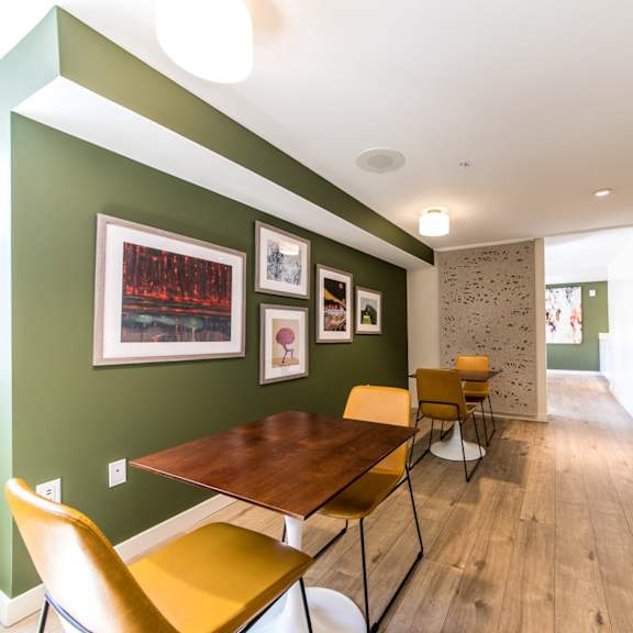 a room with a green wall and a wooden table with chairs.