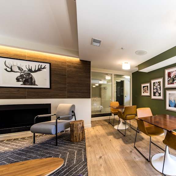 a room with a fireplace, chairs, and pictures on the wall.