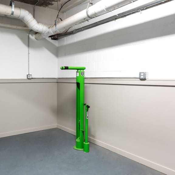 a green stand in a white room with pipes on the ceiling.
