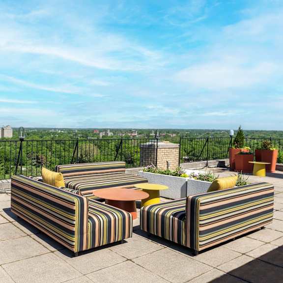 a patio with striped couches and potted plants.