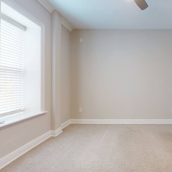 a room with a carpeted floor and a window with blinds.