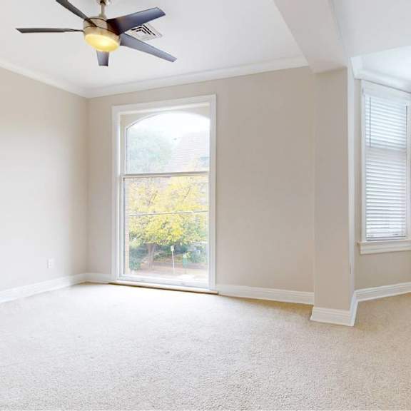 a room with a ceiling fan and a window with blinds.